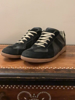 Svarta sneakers med mockadetaljer - Snygga svarta gats från masion margiela. Storleken är 43 och skorna har inga hål eller och är i mycket bra skick. Hör av vid funderingar