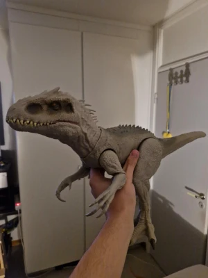 Grå dinosauriefigur leksak - Säljer en stor grå dinosauriefigur i plast med detaljerade tänder, klor och taggar längs ryggen. Perfekt för dig som gillar dinosaurier eller vill ha en cool dekoration till rummet. Figuren har rörliga ben och armar. Något du kan ge till dina barn om dem gillar dinosaurier. 