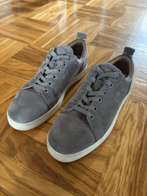 Gråa sneakers från Christian Louboutin - Snygga gråa sneakers från Louboutin, Gråa  med vit sula. Säljer nu dessa skor för 999kr! Om du har några funderingar så är det bara att skriva! 