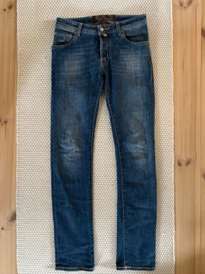 Jacob Cohen 622 Comfort - Jag säljer ett par Jacob Cohen jeans i modell 622 comfort. Jeansen är av mycket hög kvalitet med strechigt jeanstyg för extra komfort. Jeansen är en slim fit modell. Klassisk femficks design. Ytterbenlängden är 103 cm och midjemåttet är 38 cm. Jeansen är i en snygg mörkblå tvätt utan slitningar. Storlek 30. Jag är öppen för frågor och mer bolder vid behov, tveka inte! 