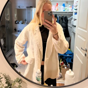 Oversized vit kavaj i linne-look - Från &Other Storiers. Stilren oversized beige kavaj med avslappnad passform och klassisk krage. Kavajen har en ficka framtill och är tillverkad i linne.