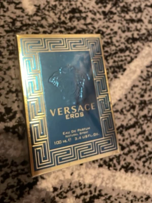 Versace Eros Eau de Parfum 100 ml - Versace Eros Eau de Parfum i en lyxig blå och guld förpackning med klassiskt grekiskt mönster och Medusahuvud. Flaskan rymmer 100 ml och har en exklusiv och modern design som verkligen sticker ut i badrumshyllan.