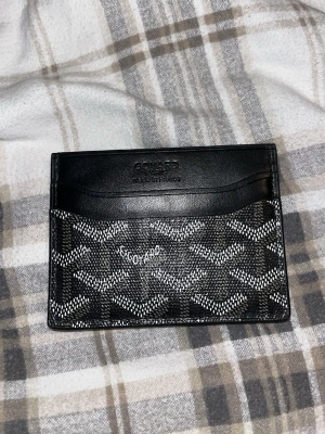 Cardholder - Snyggt svart kortfodral med klassiskt mönster i vitt och grått. Tillverkat i läder med gul insida och flera fack för kort. Perfekt för dig som vill ha en stilren och exklusiv accessoar i fickan.