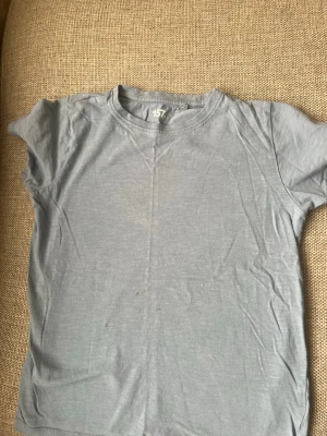 Ljusblå basic t-shirt från 157 - En enkel ljusblå t-shirt från 157 i 100% bomull. Klassisk rund halsringning och korta ärmar. Perfekt till jeans eller shorts för en avslappnad look.