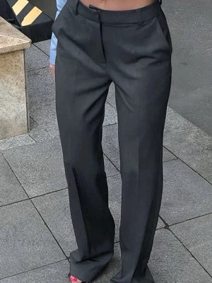 Vida grå kostymbyxor med pressveck - Säljer ett par stilrena grå kostymbyxor med hög midja och vida ben. Byxorna har klassiska pressveck framtill, hällor för skärp och diskreta sidofickor. Perfekta för en trendig och avslappnad look.