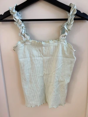 Ljusgrön ribbat linne Even&Odd - Supersöt och somrig ljusgrön ribbad topp från Even&Odd med volangdetaljer vid axelbanden och längs kanterna. 