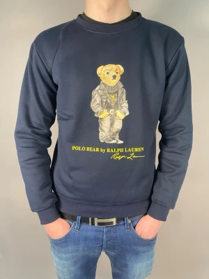 Ralph Lauren Polo bear tröja - Skick: Ny utan prislapp Storlek: M Färg: Marinblå / mörkblå Ralph Lauren tröja med Polo Bear tryck framtill. Snygg mörk färg som är enkel att matcha med jeans eller mjukisbyxor. Skön passform i storlek M, sitter bra utan att vara för tight eller för oversized som man kan se i bild tre. I super skick då den är helt ny. För lite referens på passformen är jag omkring 184cm lång och väger omkring 73kg. Skriv om du undrar något eller vill ha fler bilder!                 