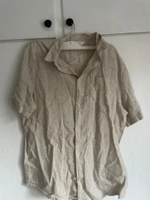 Beige linneskjorta med kort ärm - Säljer en beige linne skjorta ifrån Kappahl, strl 170. Aldrig använd, skrynklig.