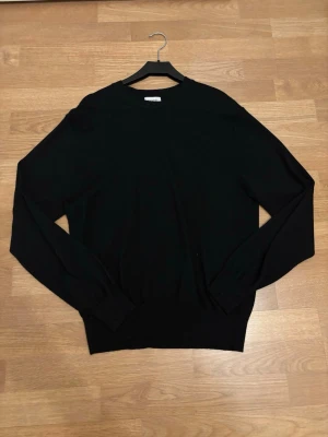 Svart merinoull tröja från Sandö - En svart, klassisk tröja med rund hals och långa ärmar. Tröjan har ribbade muddar vid ärmslut och nederkant för en snygg passform. Tröjan är lätt att matcha med andra plagg och den är otroligt mjuk. Passar alla årstider och sitter bra på kroppen. Storleken är M men passar förmodligen också som S. Hör gärna av vid minsta fundering eller fråga!