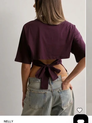 Vinröd croppad topp med knyt från Nelly - Trendig vinröd croppad topp från Nelly med korta ärmar och snygg knytning i ryggen. Toppen har en loose passform och är tillverkad i mjukt bomullsmaterial. Perfekt för dig som vill ha en unik och stilren look.