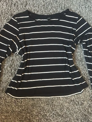 Svartvit randig långärmad topp - Snygg svart långärmad topp med vita horisontella ränder. Klassisk rund halsringning och mjukt, stretchigt material som sitter bekvämt. Perfekt att matcha med jeans eller kjol för en enkel och stilren look.