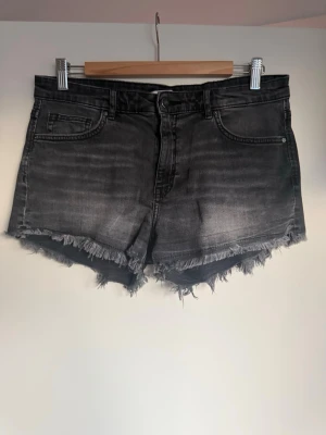 Svarta jeansshorts med fransig kant - Snygga svarta jeansshorts med fransig, rå kant och klassisk femficksdesign. Shortsen har en något tvättad look och normal passform. 