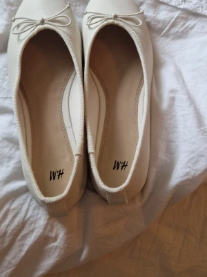  ballerinaskor från H&M - Säljer ett par klassiska ljus biegea/vita ballerinaskor från H&M. Skorna är lite små i storlek. Använt 1 gång.