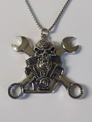 Metallhalsband med dödskalle och verktyg - Kedjehalsband i silverfärgad metall med ett stort hänge format som en motor, dödskalle och två korsade skiftnycklar. Detaljerad design med fina detaljer. Perfekt för dig som gillar motorcyklar eller mekanik. Materialet rostfritt stål 