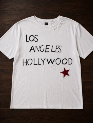 Vit t-shirt Los Angeles Hollywood - Vit t-shirt med svart text 'LOS ANGELES HOLLYWOOD' och en röd stjärna framtill. T-shirten har korta ärmar, rund hals och några slitna detaljer vid axeln och magen för en trendig look. Perfekt för dig som gillar streetstyle.