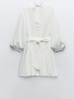 Vit kort klänning med knappar Zara - Superfin vit kort klänning från Zara med knappar framtill, markerad midja med knytskärp och trekvartsärmar. Klänningen har diskret broderat mönster och lätt volym i ärmarna för en trendig look.