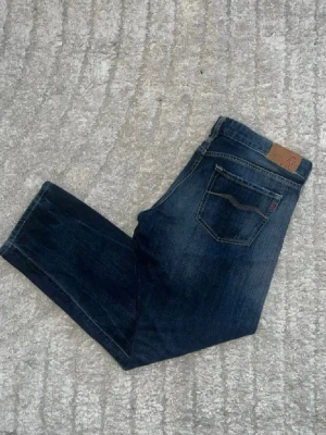 Replay jeans - Mörkblåa jeans från Repaly med en snygg fade. Midja 41cm, längd 88cm. Obs jeansen har små defekter - se bild. JAG SKICKAR EJ FLER BILDER NÄR JAG BÄR JEANSEN! för bättre inblick i passformen rekommenderar jag att googla på modellnamnet. För storleksguide kolla måtten noggrant då jeansen alltid kan vara uppsydda heller krympta och jag ej tar emot returer :) s6,5