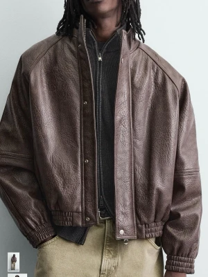 Mörkbrun skinnjacka med resår - Säljer en mörkbrun skinnjacka med hög krage och tryckknappar framtill. Jackan har resår vid ärmslut och midja för en avslappnad passform. Perfekt för dig som gillar en klassisk men cool look. Köpt på Zara. Oanvänd