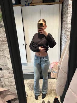 Ljusblå bootcut jeans - Säljer ett par ljusblå bootcut jeans med klassisk femficksdesign och hög midja. Jeansen har en snygg passform som framhäver benen och är tillverkade i denim med lite stretch för extra komfort. Perfekta för dig som gillar en avslappnad och trendig look.