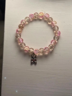 Pärlarmband med nalleberlock - Säljer ett sött handgjort  armband av mig med pärlor i rosa och transparent/beige. Armbandet har en liten nalleberlock i metall som hänger ner. Perfekt accessoar för dig som gillar gulliga detaljer  (18cm omkrets❤️)