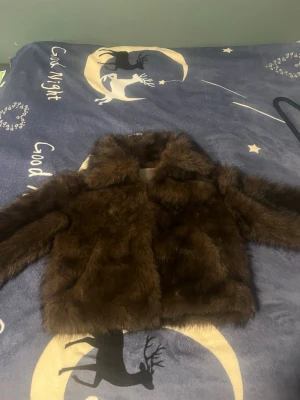 Mörkbrun fuskpälsjacka från Amisu - Säljer en fluffig mörkbrun fuskpälsjacka från Amisu. Jackan har klassisk krage, helsvart innerfoder och stängs framtill. Perfekt för dig som vill ha en trendig och varm look under vintern. Har aldrig använt men har ej prislappen kvar. 