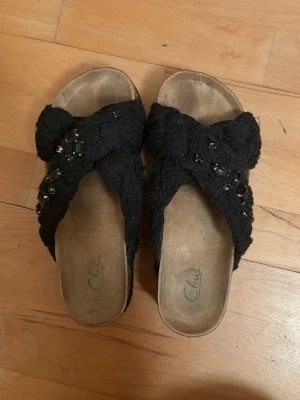 Svarta sandaler från Clou - Trendiga flätade sandaler ifrån Clou med dekorativa stenar. Använda och tecken på slitage vid sulan, samt att några stenar fallit bort, men inget som påverkar helhetsintrycket. Storlek 39, nypris 449. Hör av er vid frågor. Pris går att diskutera💌