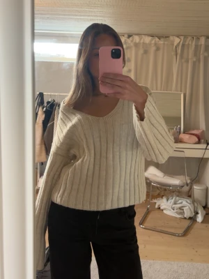 Beige ribbstickad tröja New Look - Säljer en beige ribbstickad tröja från New Look med v-ringning och långa ärmar. Tröjan har en avslappnad passform och är gjord i mjukt stickat material, perfekt för att hålla sig varm och snygg. Enkel att matcha med jeans eller kjol.