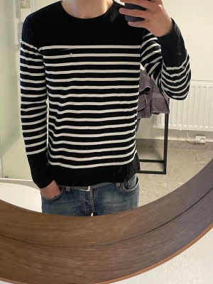 Randig svartvit tröja från Scotch & soda | L - Säljer en svart långärmad tröja från Samsoe Samsoe med vita horisontella ränder. Tröjan har rund halsringning och en liten bröstficka. Perfekt för en stilren och avslappnad look.