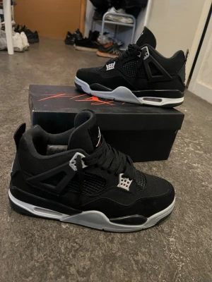 Svarta Air Jordan 4 Retro sneakers - Säljer ett par Air Jordan 4 sneakers. Skorna har meshpaneler på sidorna, plastdetaljer och den klassiska Jumpman-loggan på hälen. Tjock sula med synlig Air-enhet och skön passform. Perfekta för dig som gillar streetwear.