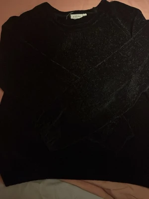 Svart sammets-tröja från Kappahl - Mjuk och stilren svart tröja i sammet från Kappahl. Tröjan har rund halsringning och långa ärmar, perfekt för dig som gillar en enkel men ändå lyxig look. Passar till både jeans och kjol för en trendig outfit.