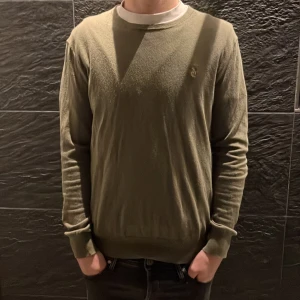 Olivgrön tröja från Polo Ralph Lauren - Säljer en stilren olivgrön tröja från Polo Ralph Lauren i slim fit. Tröjan har långa ärmar och en diskret logga på bröstet. Perfekt för en avslappnad men ändå elegant look. Perfekt nu till vintern och även våren som kommer. Skriv för mer info.
