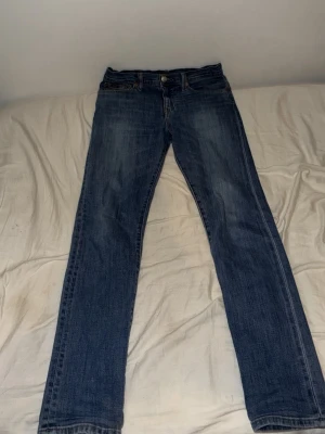 Klassiska blå raka jeans - Ett par klassiska blå jeans med rak passform och femficksdesign. Jeansen har normal midja och subtila slitningar för en avslappnad look. Perfekta till sneakers eller boots och funkar året runt.