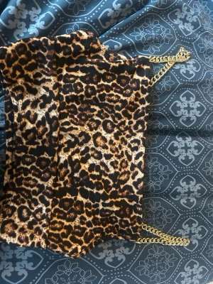 Leopardmönstrad crop top med guldkedjor - Snygg leopardmönstrad crop top med tunna axelband i guldfärgad kedja. Toppen har en figurnära passform och är gjord i ett mjukt, stretchigt material. Perfekt för dig som vill sticka ut med ett djurmönster och coola detaljer.
