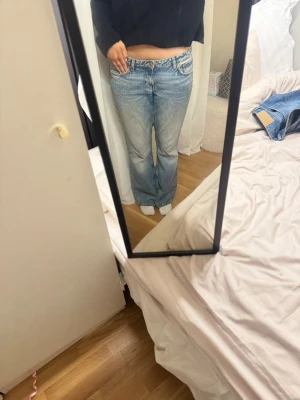 Ljusblå raka jeans med låg midja - Säljer ett par ljusblå jeans med rak passform och låg midja. Jeansen har klassisk femficksdesign och subtila slitningar för en avslappnad look. Perfekta till vardags och passar till det mesta i garderoben. 