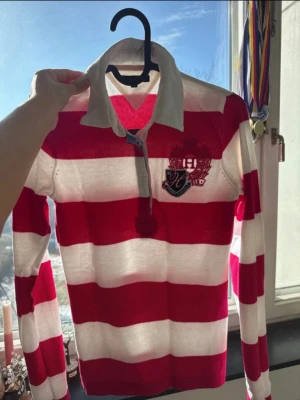 Randig långärmad skjorta med krage - Säljer en cool långärmad skjorta med breda röda och vita ränder, klassisk krage och knappar vid halsen. 