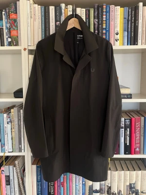 UBR jacka - Snygg mörkgrön rock från UBR med minimalistisk design och diskret logotyp på bröstet. Rocken har klassisk krage, dold dragkedja och knappstängning. Materialet är tekniskt och vattenavvisande, perfekt för dig som vill ha stil och funktion. Nypris 6500kr, nästan helt ny