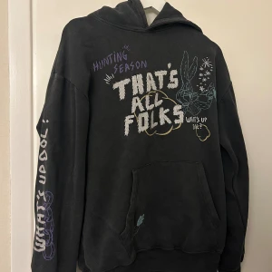Svart hoodie med Looney Tunes-tryck - Cool svart hoodie med färgglada Looney Tunes-tryck och text som 'THAT'S ALL FOLKS' och 'WHAT'S UP DOC'. 