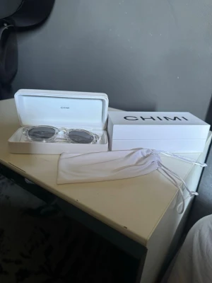 Chimi transparenta solglasögon - Snygga solglasögon från Chimi med transparent båge och mörka runda glas. Kommer med originalförpackning och vit tygpåse. Perfekt accessoar för att lyfta din stil under soliga dagar. Aldrig andvänt dem, dem är i nyskick och ny pris för dem här chimi solglasögonen är 1400kr.