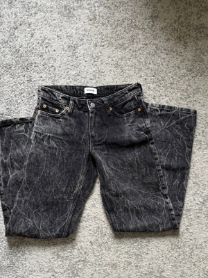 Svarta raka jeans från Weekday - Säljer ett par svarta jeans från Weekday med rak passform och coolt tvättad look. Jeansen har fem fickor, knappgylf och kontrastsömmar. Materialet är klassisk denim i bomull. Perfekta för dig som gillar en avslappnad och trendig stil. Storlek 24, Innerbensmått 78.