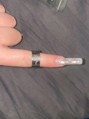Silvrig ring med orm-motiv - Cool och bred silvrig ring i metall med ingraverat orm-motiv runt om. Ringen har en modern och edgy vibe, perfekt för att lyfta din stil med en unik detalj. Passar dig som gillar statement-smycken och vill sticka ut lite extra.