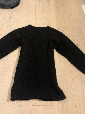 Svart stickad tröja från Lindex - Mysig svart stickad klänning från Lindex med lång ärm och rak passform. Perfekt för lager-på-lager och enkel att matcha med olika outfits. Klänningen är i ett mjukt material och har en klassisk rund halsringning. (Omsydd till kortare)