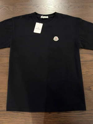 Plain black t-shirt with logo - A plain black t-shirt with a colored logo in the size M