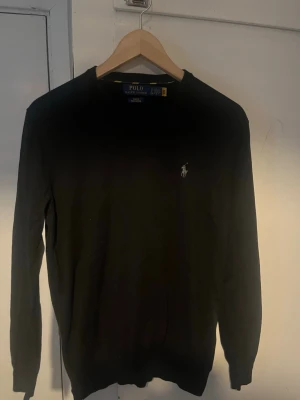 Svart tröja från Polo Ralph Lauren - Klassisk svart tröja från Polo Ralph Lauren med rund halsringning och den ikoniska broderade loggan på bröstet. Tröjan har lång ärm och är tillverkad i mjukt material som känns skönt mot huden. Perfekt för en stilren och enkel look. Passar S/m ( står inte för returer) (ni får själva bedöma skicka på varan med fotonen) köpt på zalando. Knappt använd