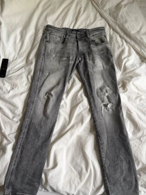 Grå slitna jeans från replay nk - Säljer ett par grå jeans från replay med slitningar som är köpta på nk för 2200kr. Jeansen har passformen anbass. Dessa jeans är väldigt sällsynta och är ofta slutsålda. Jeansen har inga defekter. W31 L32
