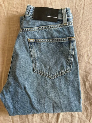 Blå jeans från BLK DNM - Klassiska blå jeans från BLK DNM i 100% bomull. Modellen har raka ben, hög midja och femficksdesign med tydliga kontrastsömmar. 