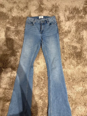 Ljusblå bootcut jeans  - Säljer ett par ljusblå bootcut jeans. Jeansen har utsvängda ben och är tillverkade i mjuk denim med lite stretch för skön passform. Skulle klassa de som högmidjade men jag som inte gillar det har använt de ändå! Säljs pga: lite för stora i midjan