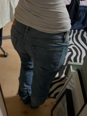 Blå slitna Levis jeans - Säljer ett par blå jeans från Levis med slitningar på låren. Jeansen har klassisk femficksdesign och låg midja🩵