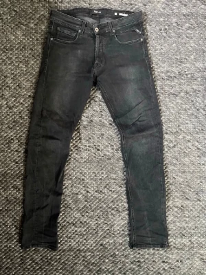 Replay Grover jeans svart - Säljer ett par svarta grover jeans från Replay med klassisk femficksdesign och diskreta slitningar. Jeansen har normal midja, perfekt för en trendig och avslappnad stil. Materialet är stretchigt för extra komfort. Fraktar samma dag annars dagen efter🚚🤩