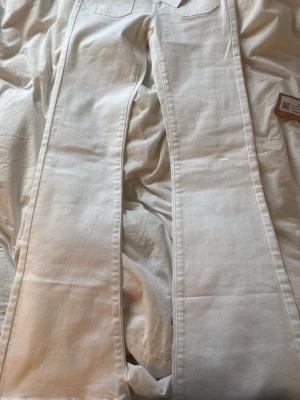 Vita utsvängda jeans - Säljer ett par vita jeans med utsvängda ben och låg midja. Jeansen har klassiska bakfickor och är tillverkade i ett tjockare denimtyg. Perfekta för dig som vill ha en trendig och clean look.