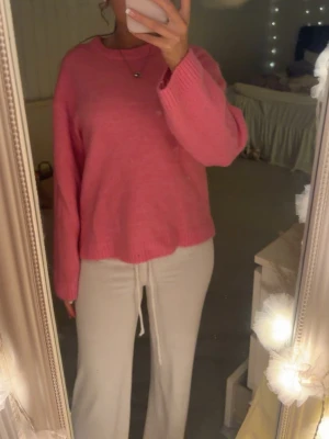 Rosa oversized stickad tröja - Mysig rosa stickad tröja med oversized passform och långa ärmar. Tröjan har ribbade muddar vid ärmslut och nederkant samt rund halsringning. Perfekt för att hålla sig varm och ändå se trendig ut.